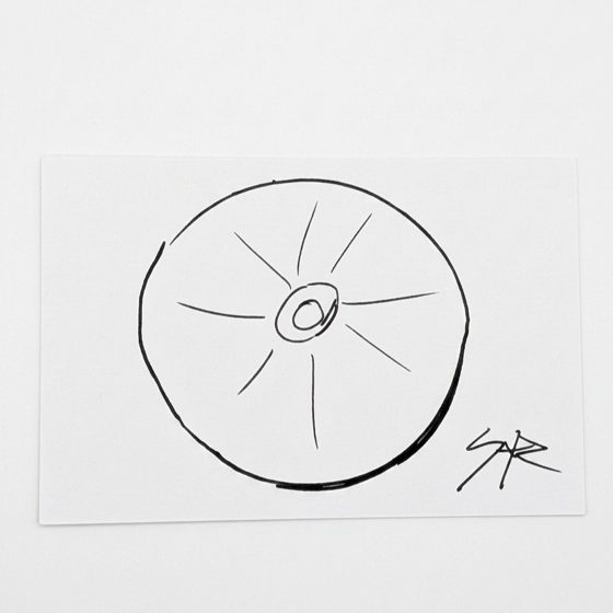 Minimal black marker drawing by SKR of a spoked wheel on white card, signed SKR